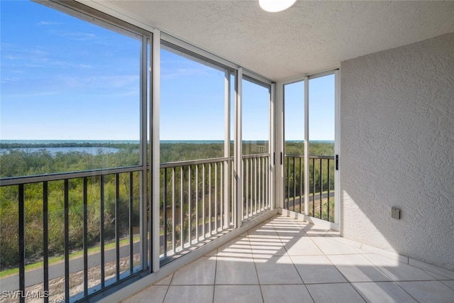 6849 Grenadier Blvd Unit 603, Naples, FL 34108 - unfurnished sunroom featuring a textured wall, tile patterned flooring, a water view, a textured ceiling, and a wall of windows