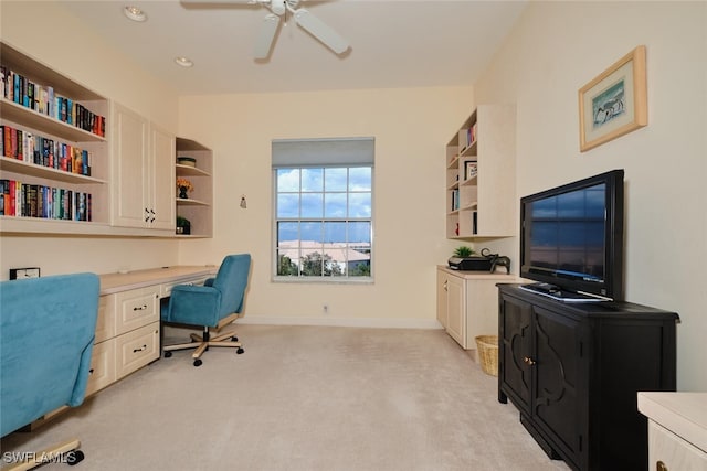 office with built in desk, ceiling fan, and light carpet