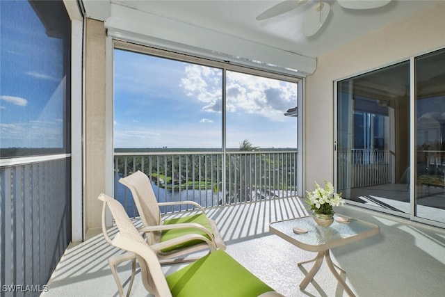 sunroom / solarium with ceiling fan and a water view