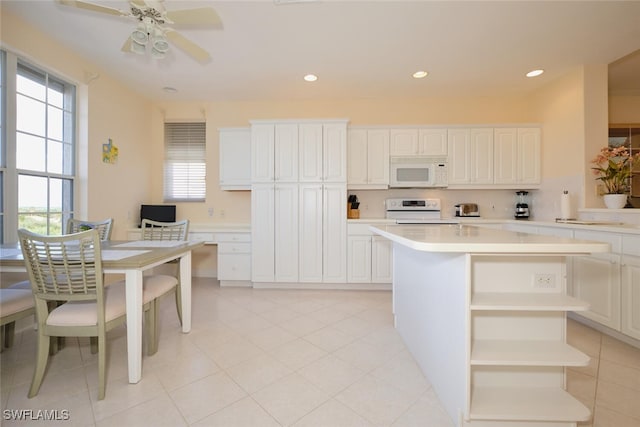 kitchen with white appliances, ceiling fan, white cabinetry, and a kitchen island