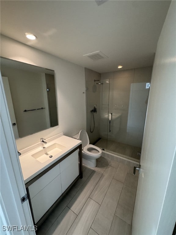 bathroom with toilet, a stall shower, vanity, and recessed lighting