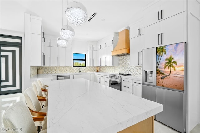 kitchen featuring pendant lighting, a breakfast bar, white cabinetry, appliances with stainless steel finishes, and custom range hood