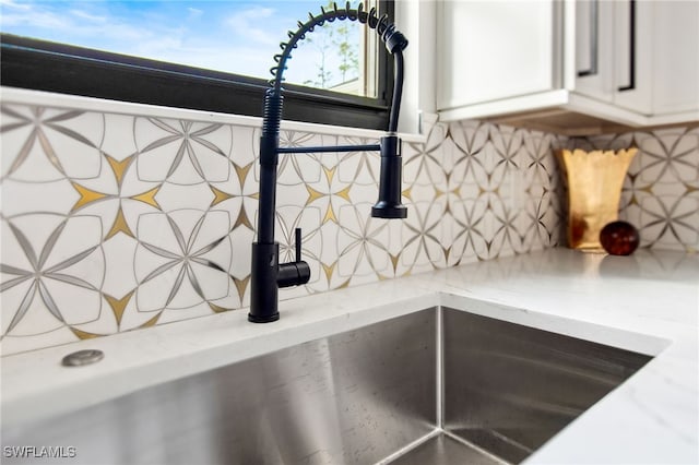 details featuring white cabinets, backsplash, and sink