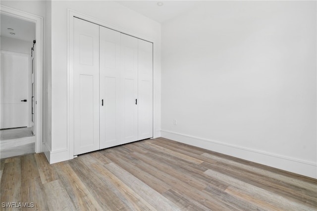 unfurnished bedroom with light wood-type flooring and a closet