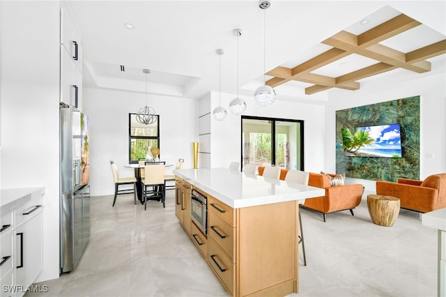 kitchen featuring stainless steel fridge, decorative light fixtures, a kitchen breakfast bar, white cabinets, and a center island