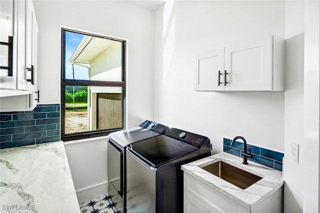 laundry room featuring sink, washing machine and clothes dryer, and cabinets