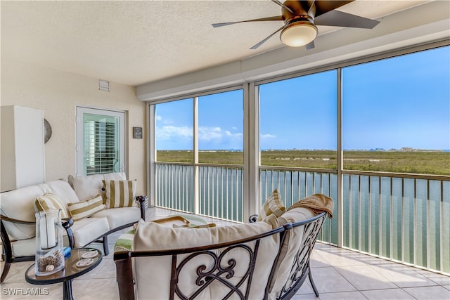 sunroom featuring a water view and ceiling fan