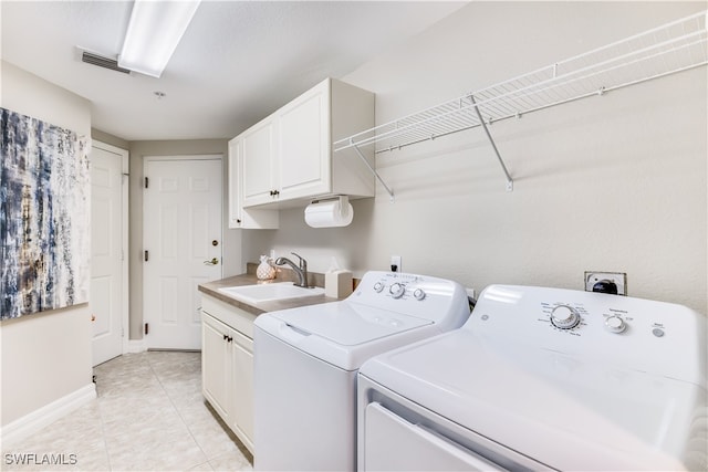 clothes washing area featuring cabinets, washer and clothes dryer, sink, and light tile patterned floors