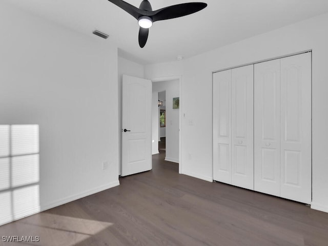 unfurnished bedroom featuring dark hardwood / wood-style flooring, ceiling fan, a closet, and multiple windows