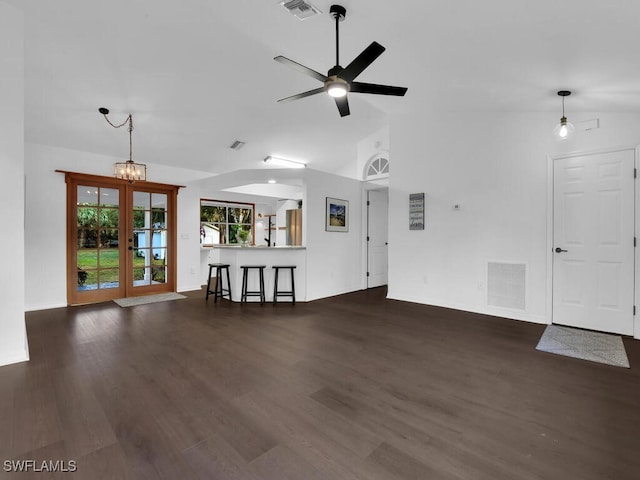 unfurnished living room with french doors, ceiling fan with notable chandelier, dark hardwood / wood-style floors, and lofted ceiling