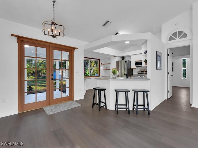 kitchen featuring kitchen peninsula, french doors, appliances with stainless steel finishes, decorative light fixtures, and white cabinetry