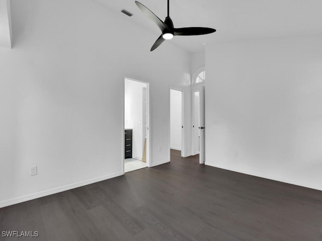 unfurnished living room featuring a towering ceiling, dark hardwood / wood-style floors, and ceiling fan