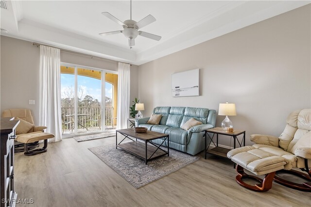 living room featuring a tray ceiling, hardwood / wood-style flooring, and ceiling fan