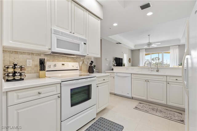 kitchen featuring a raised ceiling, sink, white cabinets, white appliances, and ceiling fan