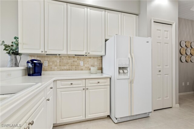 kitchen with white cabinets, light tile patterned floors, backsplash, and white refrigerator with ice dispenser