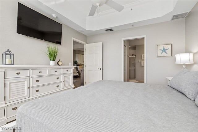 bedroom with ensuite bathroom, ceiling fan, and a raised ceiling