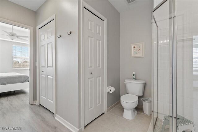 bathroom featuring ceiling fan, a shower with shower door, toilet, and wood-type flooring