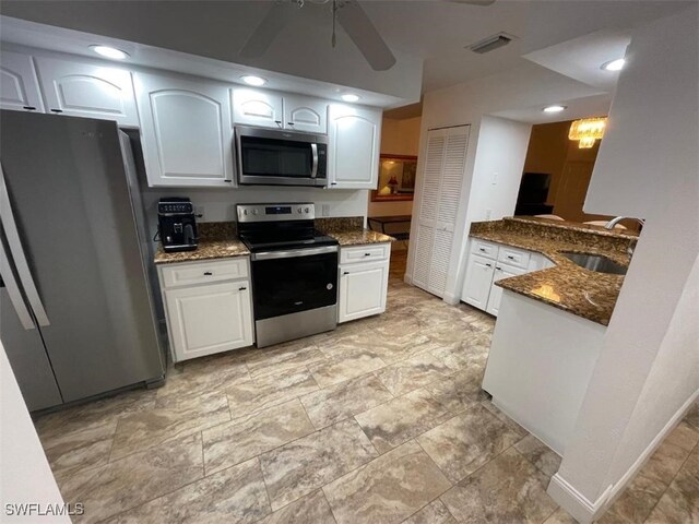 kitchen with stainless steel appliances, sink, ceiling fan, white cabinetry, and dark stone countertops