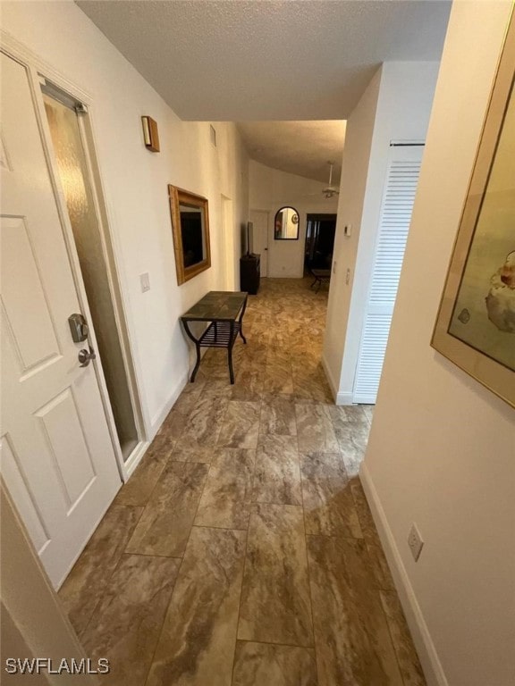 hallway featuring a textured ceiling and lofted ceiling