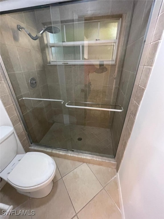 bathroom featuring toilet, tile patterned flooring, and a shower with door