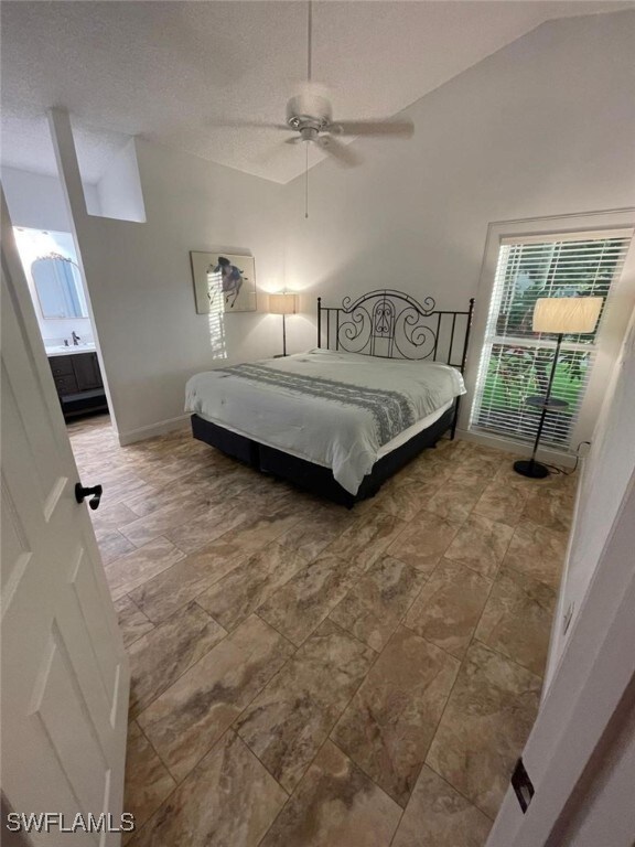 bedroom featuring ceiling fan, connected bathroom, and a textured ceiling