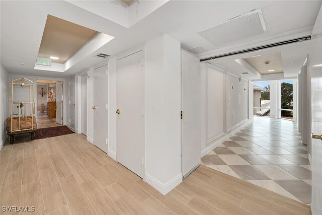 corridor with light hardwood / wood-style floors and a raised ceiling