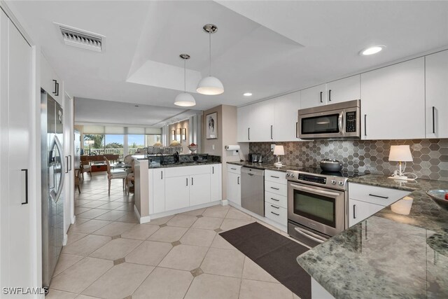 kitchen featuring white cabinetry, kitchen peninsula, stainless steel appliances, and hanging light fixtures