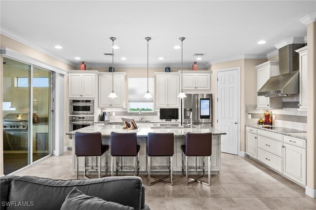 2616 Malaita Ct, Cape Coral, FL 33991 - kitchen featuring a kitchen island with sink, wall chimney range hood, appliances with stainless steel finishes, decorative light fixtures, and light stone counters
