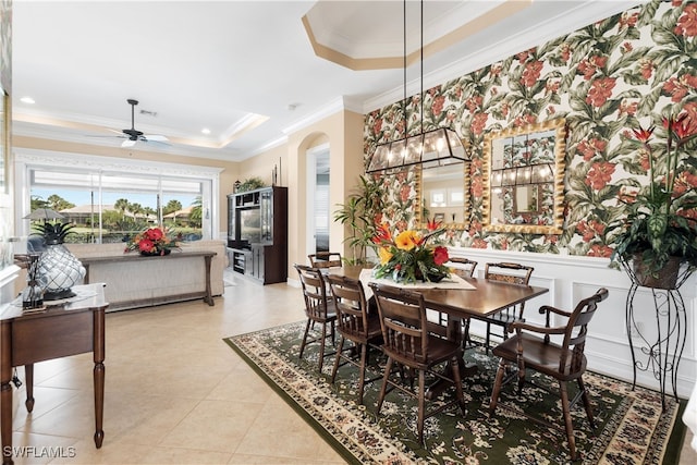 tiled dining area featuring ceiling fan, crown molding, and a tray ceiling