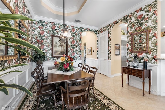 dining space with a tray ceiling and ornamental molding