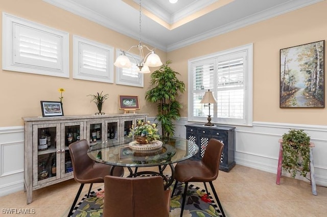 tiled dining room with a tray ceiling, an inviting chandelier, and ornamental molding