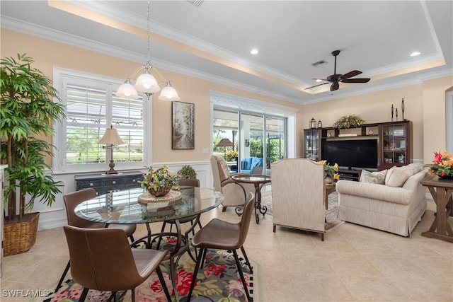 tiled dining space with ceiling fan, a tray ceiling, ornamental molding, and plenty of natural light