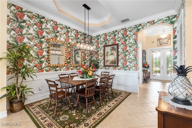 tiled dining space with a tray ceiling, french doors, and ornamental molding