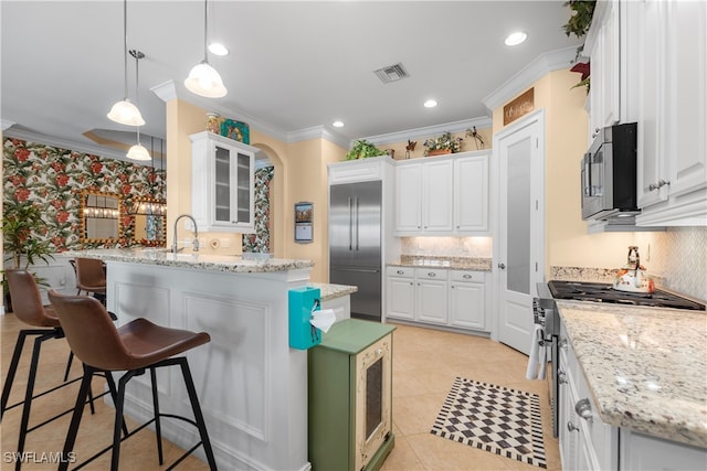 kitchen with white cabinetry, a kitchen breakfast bar, high quality appliances, and pendant lighting