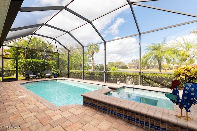 view of pool with glass enclosure, a patio, and an in ground hot tub