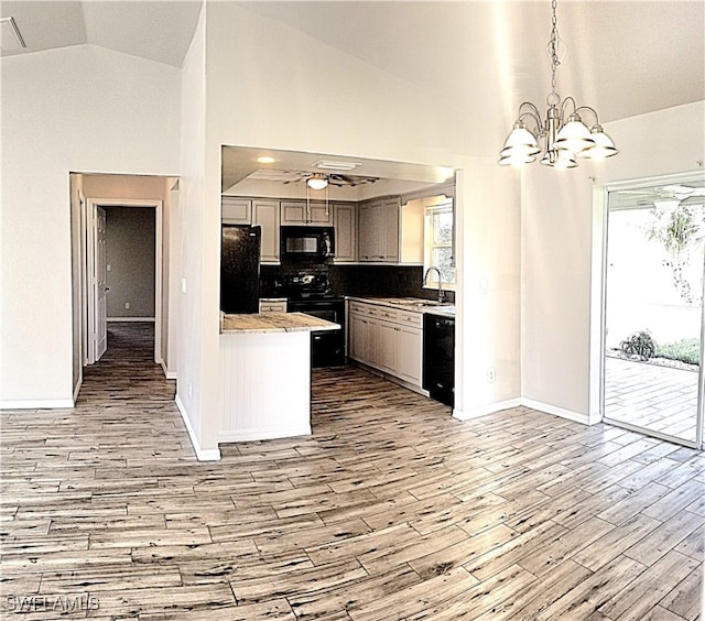 kitchen featuring sink, hanging light fixtures, black appliances, ceiling fan with notable chandelier, and light wood-type flooring