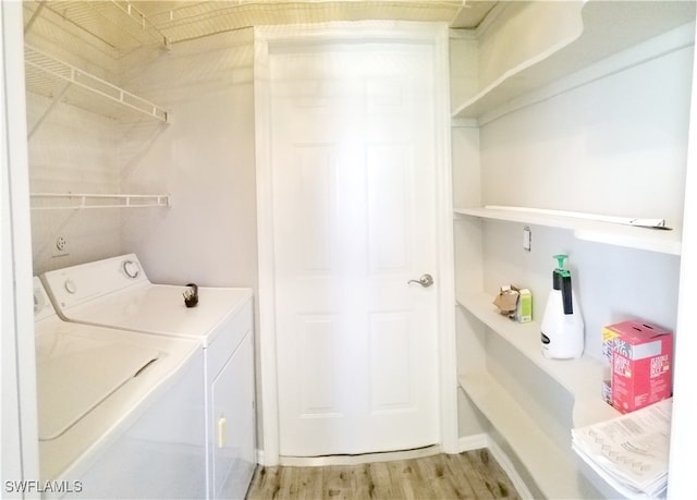 laundry area featuring washing machine and clothes dryer and light hardwood / wood-style floors