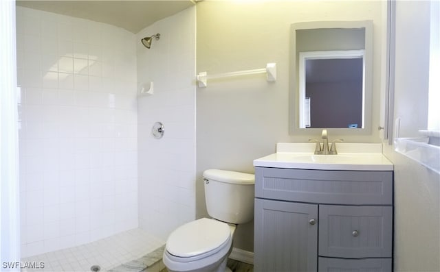 bathroom with tiled shower, vanity, and toilet