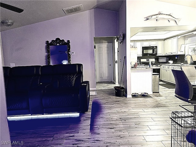 living room with light wood-type flooring, vaulted ceiling, and sink