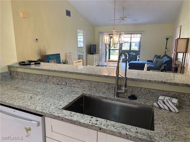 kitchen with hanging light fixtures, a notable chandelier, white dishwasher, vaulted ceiling, and white cabinets