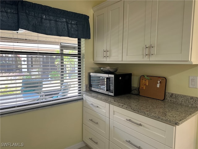 kitchen featuring light stone countertops and white cabinetry