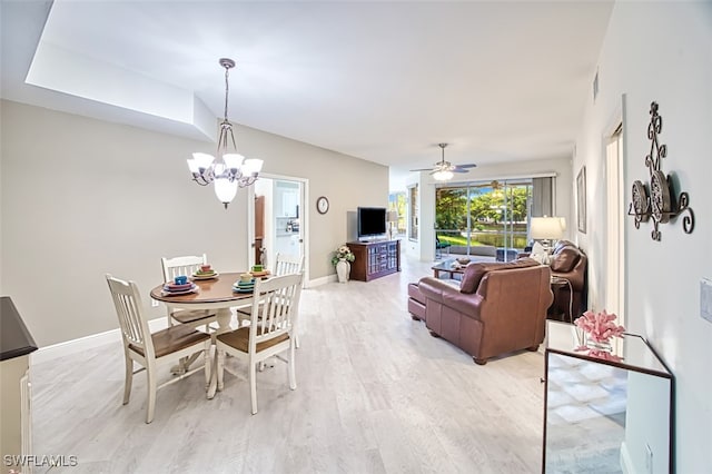 dining space with ceiling fan with notable chandelier and light wood-type flooring