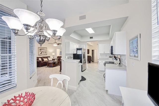 dining space featuring ceiling fan with notable chandelier and light hardwood / wood-style flooring