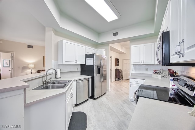 kitchen featuring stainless steel appliances, backsplash, sink, light hardwood / wood-style floors, and white cabinets