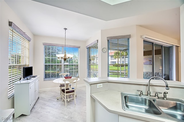 kitchen featuring light hardwood / wood-style floors, white cabinetry, sink, a notable chandelier, and pendant lighting