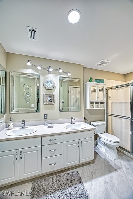 bathroom featuring a shower with shower door, vanity, and toilet