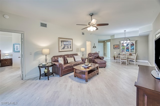 living room featuring ceiling fan with notable chandelier and light hardwood / wood-style flooring