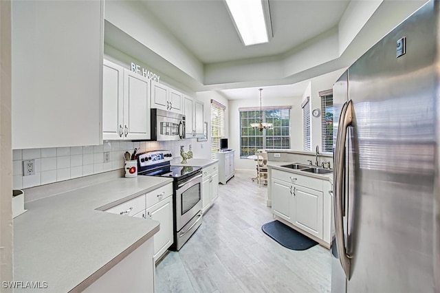 kitchen with pendant lighting, white cabinets, sink, and stainless steel appliances