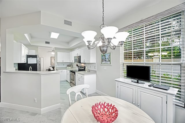 dining area featuring ceiling fan with notable chandelier and a raised ceiling