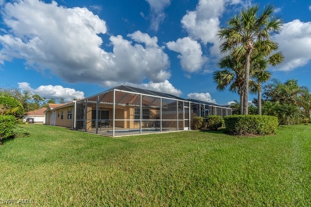 rear view of house with glass enclosure and a lawn